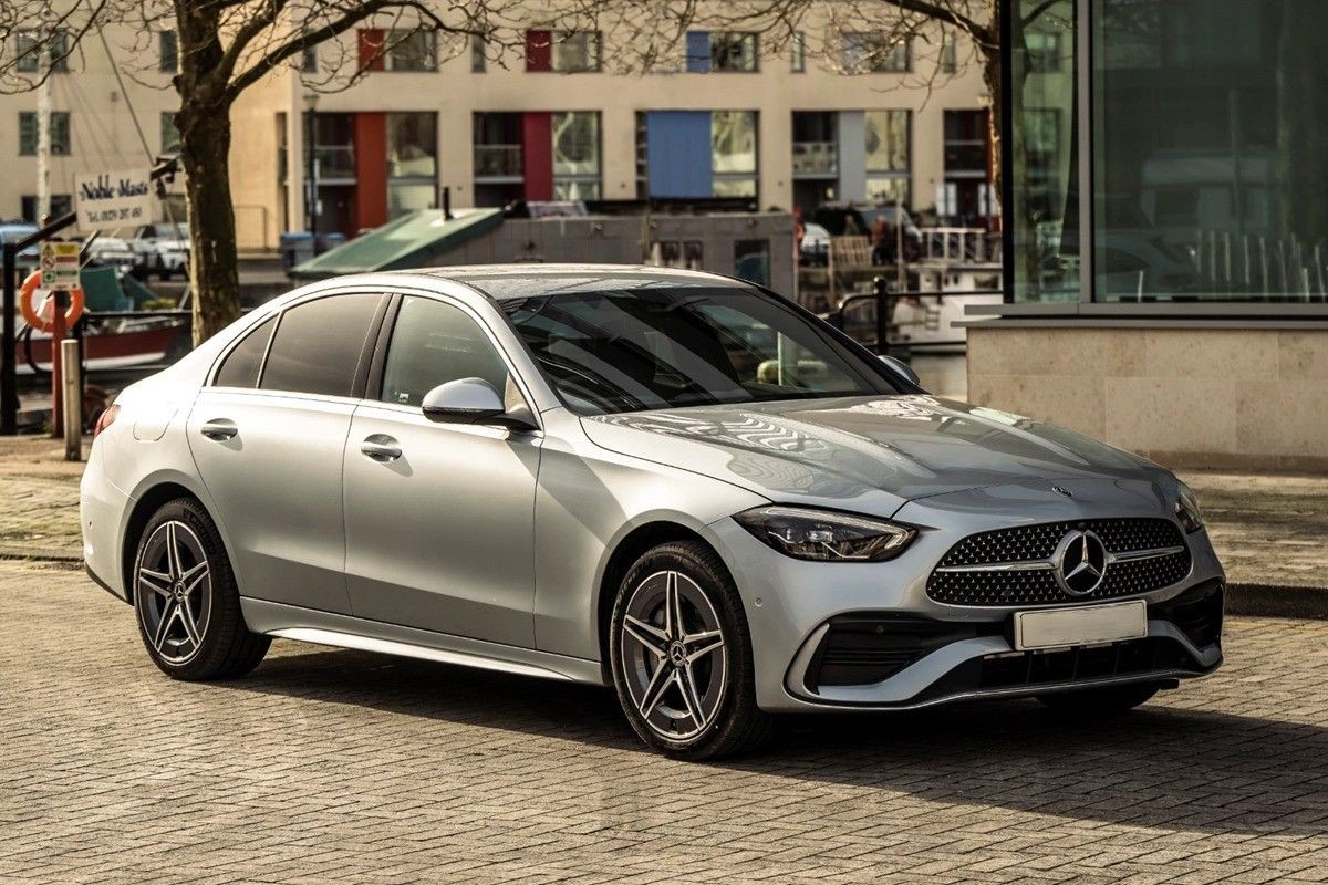 Silver luxury sedan parked on a city street with buildings in the background.